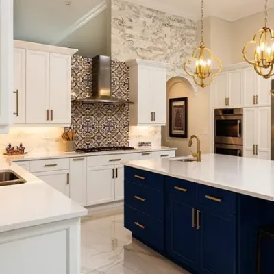 Modern kitchen with white cabinets, dark blue island, and stylish pendant lights.
